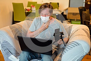 Young man having flu while vlogging and meeting online while in quarantine at home