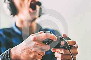 Young man having fun playing video games online using headphones and microphone - Close up male hands gamer holding a joystick