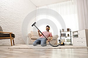 Young man having fun while vacuuming