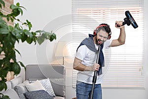 Young man having fun while vacuuming