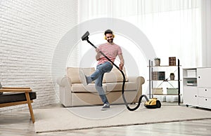 Young man having fun while vacuuming