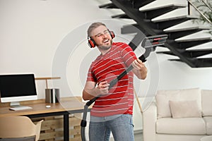 Young man having fun while vacuuming in living room