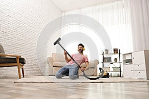 Young man having fun while vacuuming photo