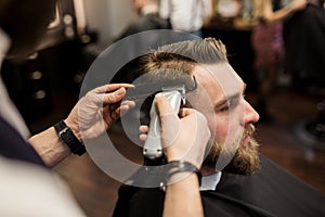 Young man having hair shaved at barber shop