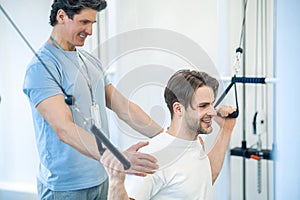 Young man having na physical therapy with instructor in the rehabilitation center