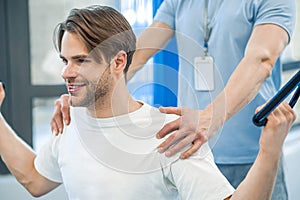 Young man having na physical therapy with instructor in the rehabilitation center