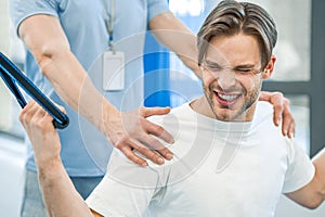 Young man having na physical therapy with instructor in the rehabilitation center