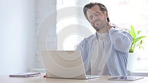 Young Man having Neck Pain while using Laptop