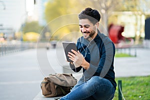 Young man having a video call on digital tablet outdoors.