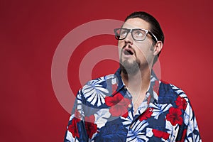 Young man in Hawaiian shirt looking upwards with mouth open