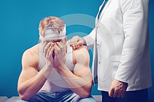 Young man with head injury in the doctor`s office. Head bandaged with a bandage