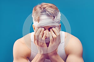 Young man with head injury in the doctor`s office. Head bandaged with a bandage