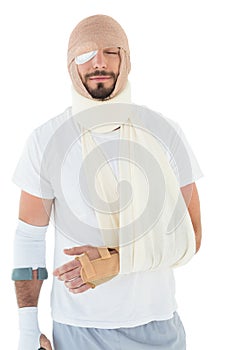 Young man with head tied up in bandage and broken hand