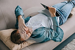 young man with headache lying on sofa