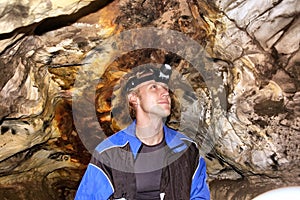 Young man with headlamp in a cave