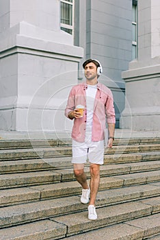 young man in headphones with laptop and coffee to go