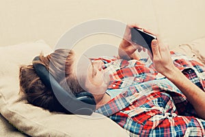 Young man in headphones with mobile phone relaxing home