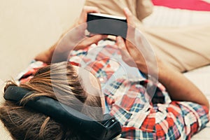 Young man in headphones with mobile phone relaxing home