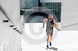 Young man in headphones running upstairs outdoors