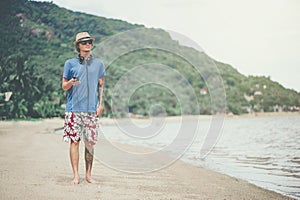 Young man in headphones and sunglasses at the beach listening to the music