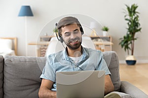 Young man in headset sitting on couch looking at laptop photo