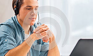 Young man in a headset works at a laptop computer. Freelancer, remote worker or student workplace. Distant work concept.