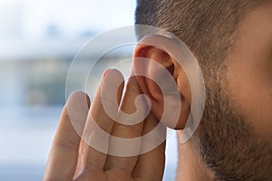 Young man with hearing problems, hearing loss or hard of hearing