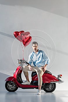 young man with heart shaped balloons sitting