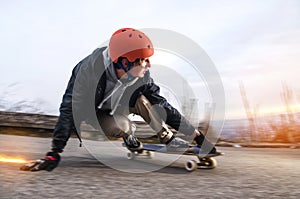 Young man in helmet is going to slide, slide with sparks on a longboard on the asphalt