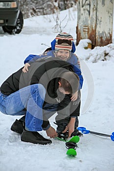 young man helps and teaches a little boy to ski. Winter entertainment of Russian people.