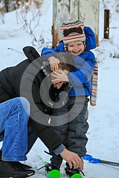 Young man helps and teaches a little boy to ski. Winter entertainment of Russian people.