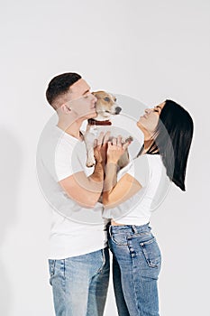 Young man and her boyfriend with their dog at studio. Young owners kissing pet. young and beautiful couple holding dog