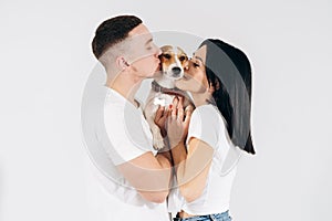 Young man and her boyfriend with their dog at studio. Young owners kissing pet. young and beautiful couple holding dog