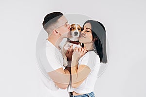 Young man and her boyfriend with their dog at studio. Young owners kissing pet. young and beautiful couple holding dog