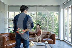 Young man hides a gift box behind, preparing to surprise girlfriend