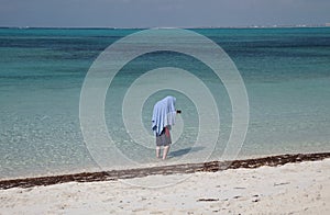 Young man hiding from the sun under a towel