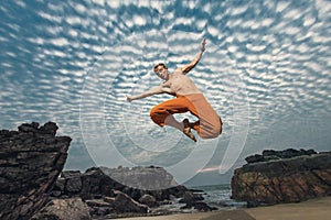 Young man high jumping on beach