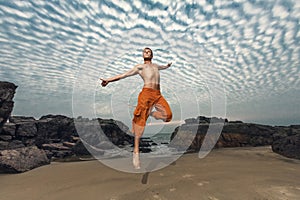 Young man high jumping on beach