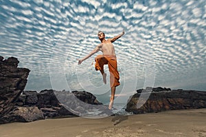 Young man high jumping on beach