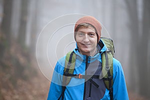 Young man hiking with backpack in a forest in winter