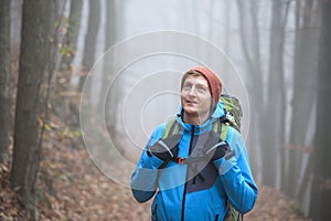 Young man hiking with backpack in a forest in winter