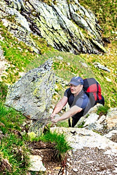 Young man hiking on difficult mountain trail with hanging cable