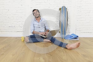 Young man in hipster modern casual style look sitting on living room home floor working on laptop