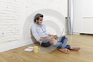 Young man in hipster modern casual style look sitting on living room home floor working on laptop