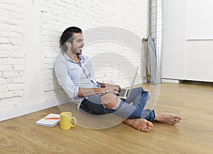 Young man in hipster modern casual style look sitting on living room home floor working on laptop