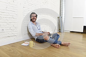 Young man in hipster modern casual style look sitting on living room home floor working on laptop