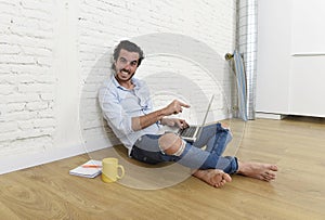 Young man in hipster modern casual style look sitting on living room home floor working on laptop