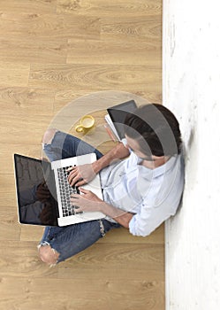 Young man in hipster modern casual style look sitting on living room home floor working on laptop
