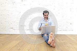 Young man in hipster modern casual style look sitting on living room home floor working on laptop