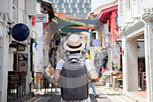 Young man hipster traveling with backpack and hat, happy Asian traveler walking at Haji Lane and Arab street in Singapore.